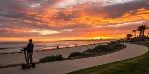 Man on a private Segway tour rides along a Coronado Island beach path at sunset.